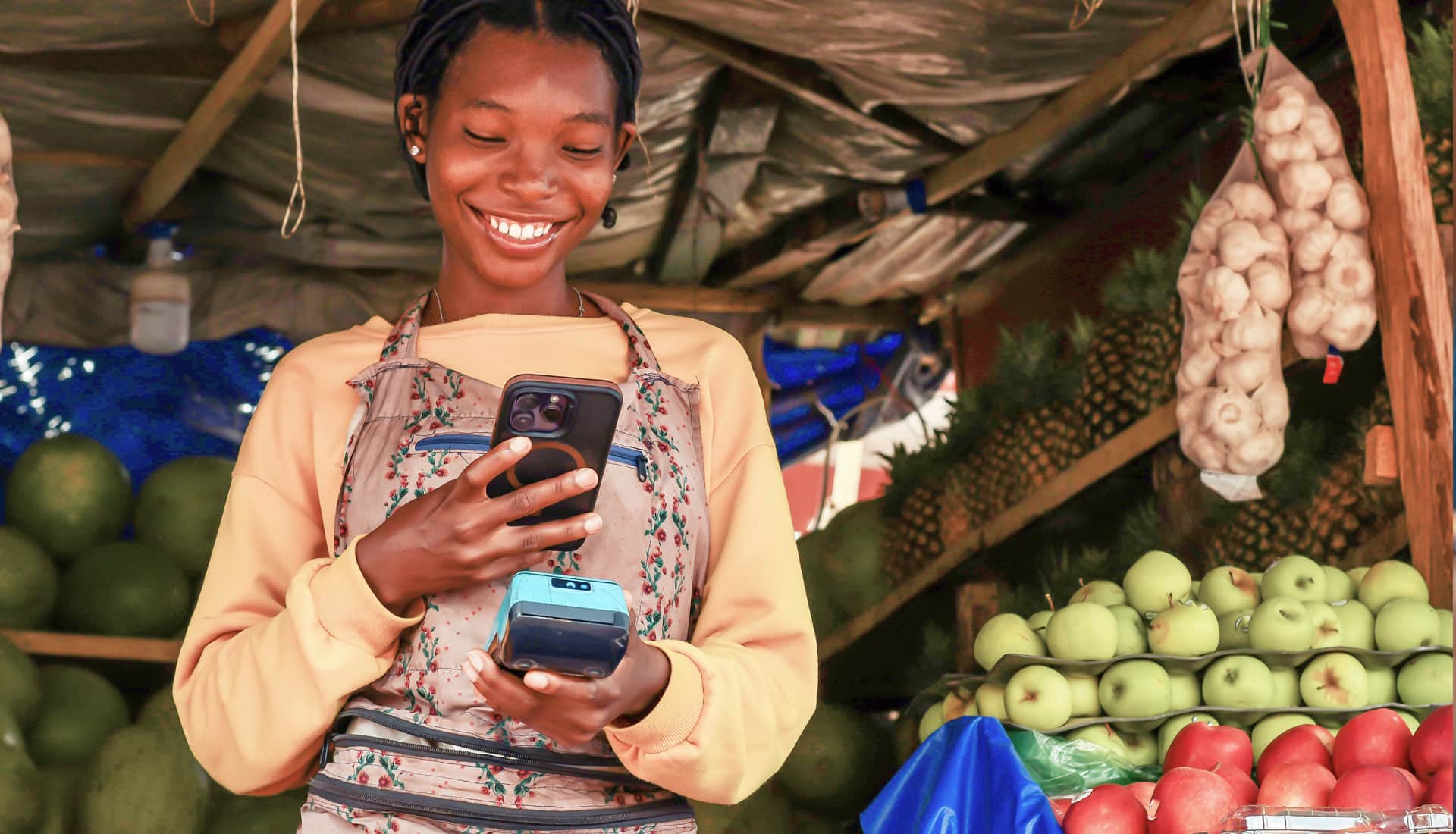 South African market vendor using a smartphone for mobile payments, representing smartphone credit building and financial inclusion