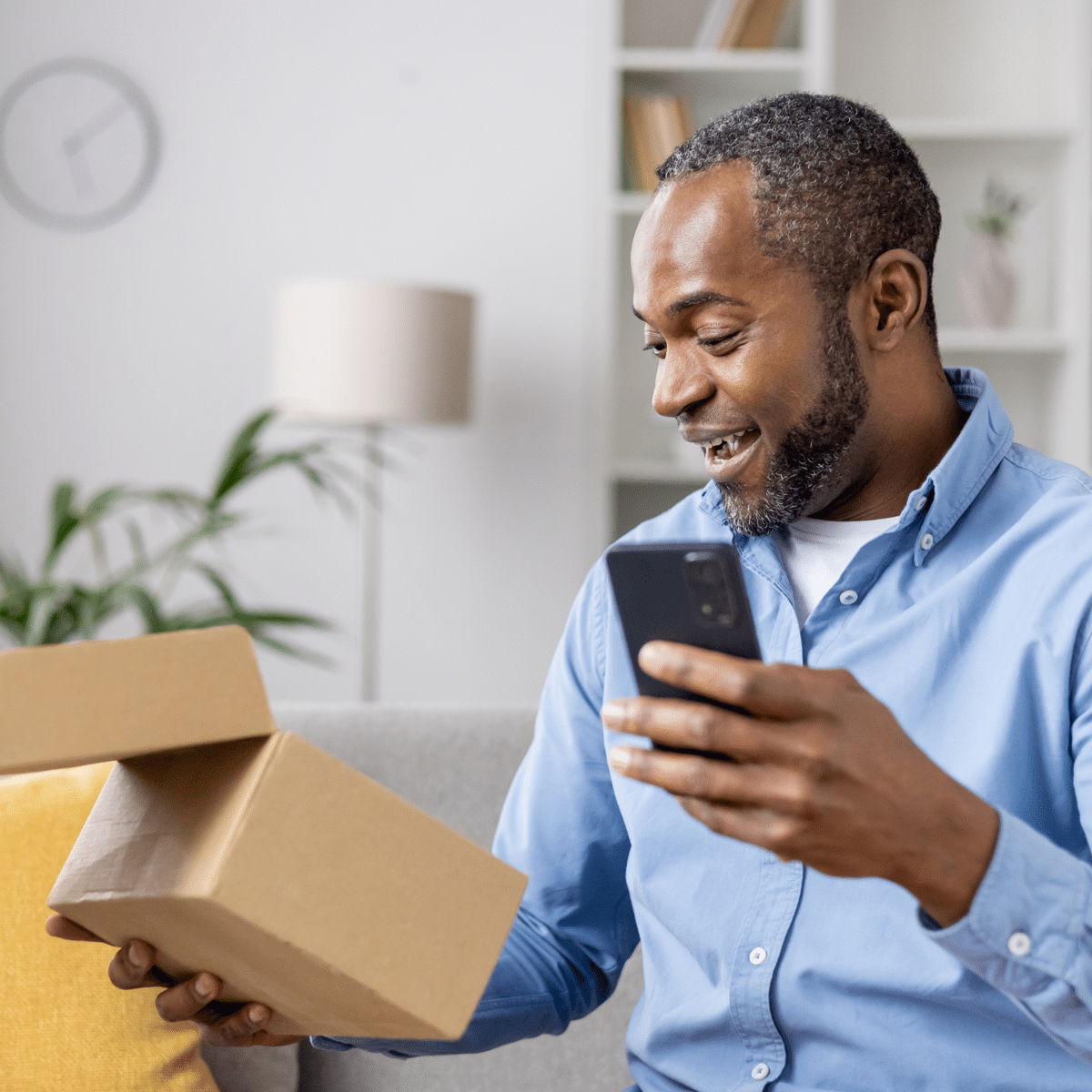 Delivery experience customer opening a delivered package while checking a smartphone at home