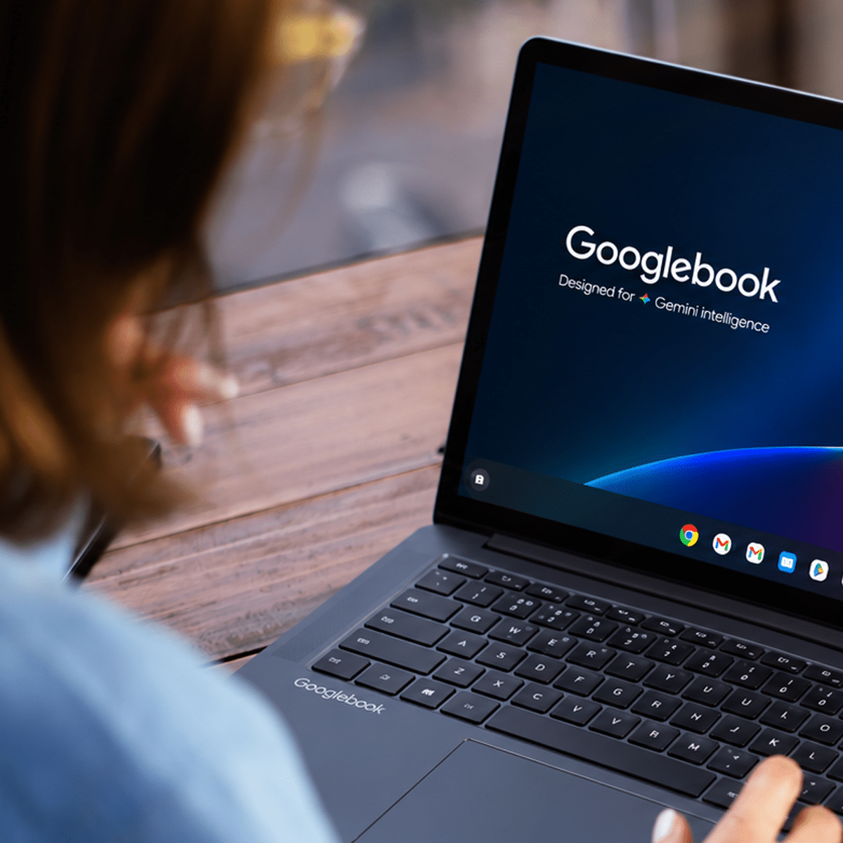 Googlebook laptop being used at a wooden desk beside a sunlit window.